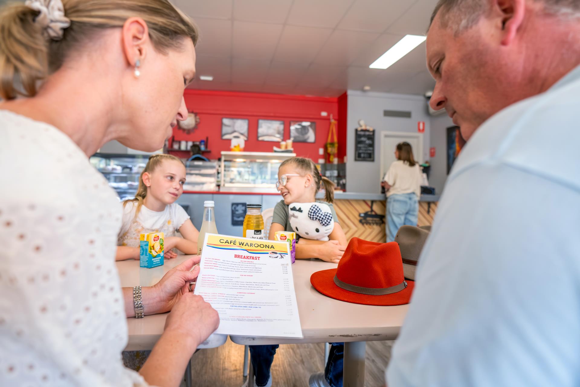 Picture of family sitting at table in cafe Waroona, looking at the menu.